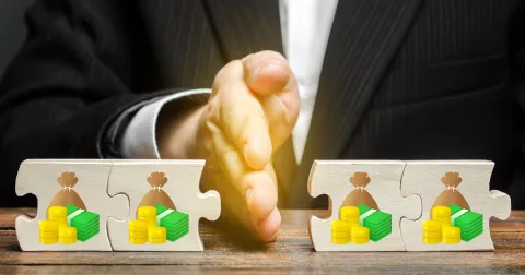 A businessman's hand separates money-themed puzzle pieces