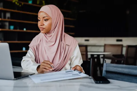 Woman in hijab looking at something on her laptop
